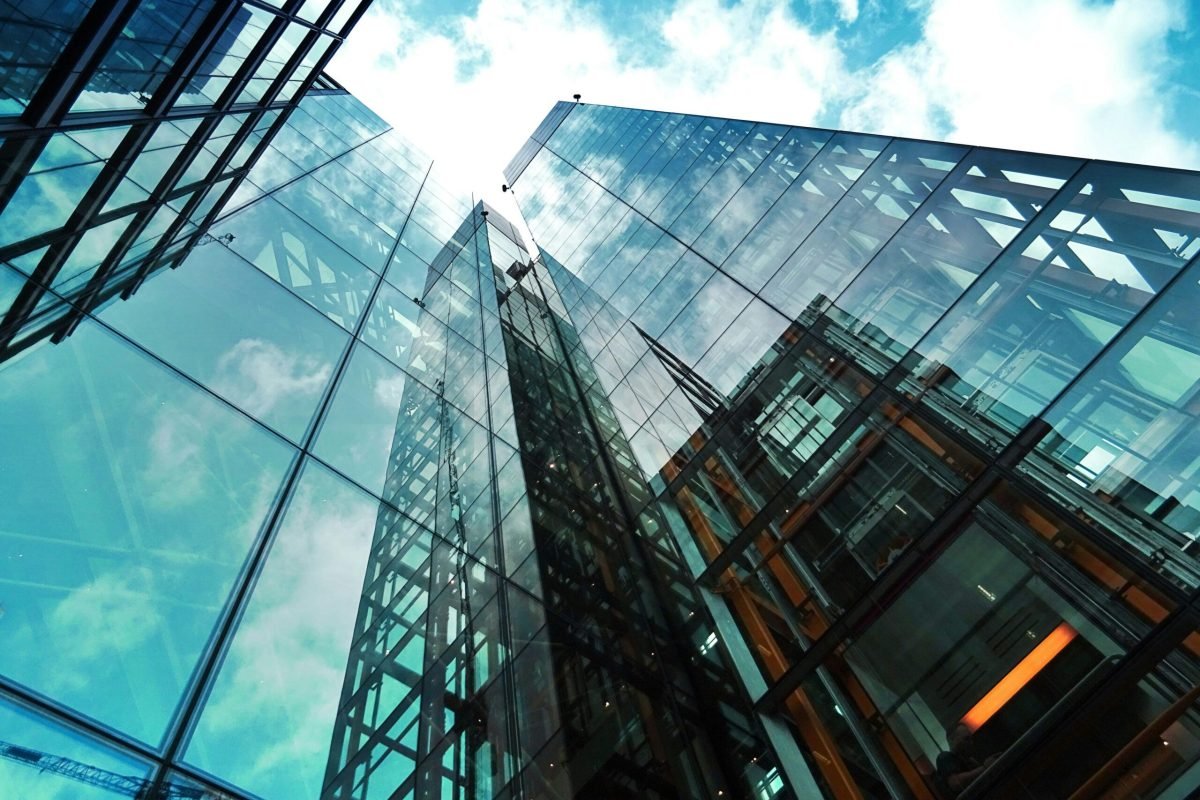 A striking view of a modern glass skyscraper reflecting the sky and clouds.